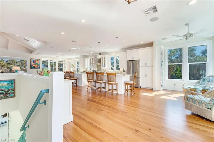 Living room with light hardwood / wood-style floors, vaulted ceiling, and ceiling fan