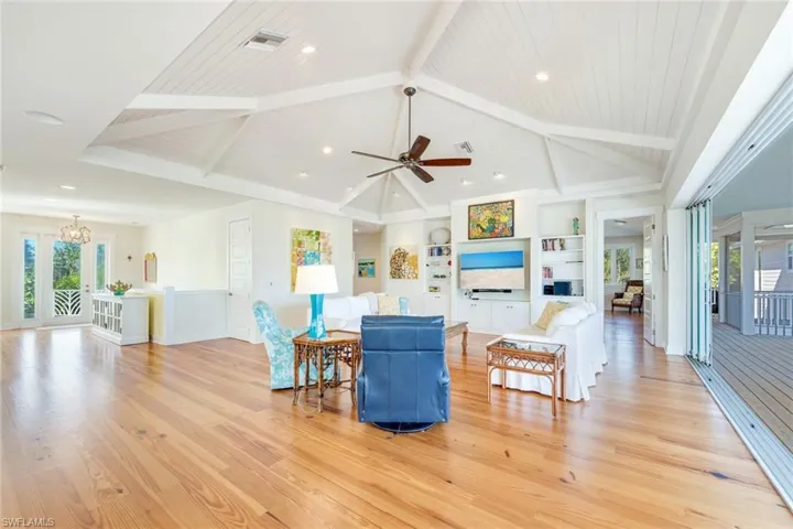 Living room with ceiling fan with notable chandelier, light hardwood / wood-style flooring, plenty of natural light, and wood ceiling