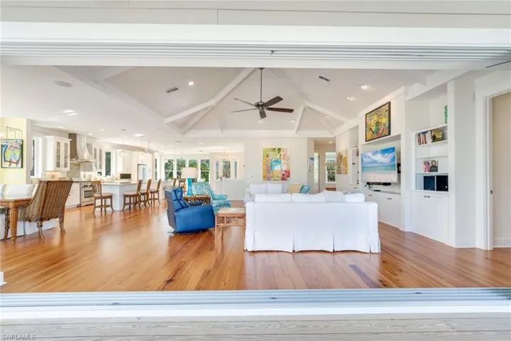 Living room featuring lofted ceiling with beams, ceiling fan, built in shelves, light hardwood / wood-style floors, and wood ceiling
