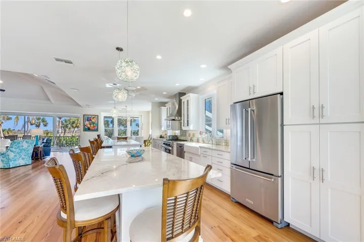 Kitchen featuring light stone counters, light hardwood / wood-style floors, decorative light fixtures, white cabinets, and high end appliances