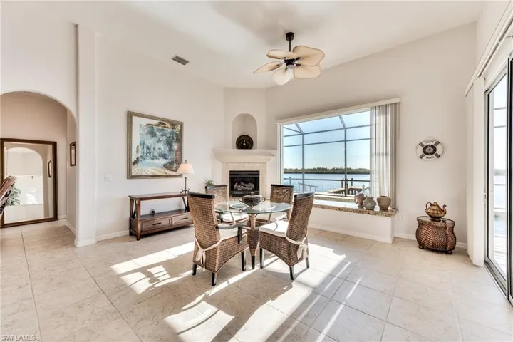 Dining room with light tile patterned floors, a water view, ceiling fan, and a tiled fireplace