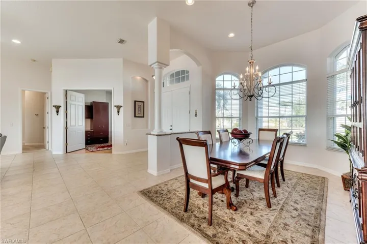 Dining area featuring light tile patterned flooring, ornate columns, and a chandelier