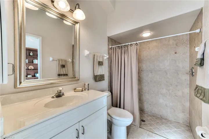 Bathroom featuring tile patterned flooring, a shower with curtain, vanity, and toilet