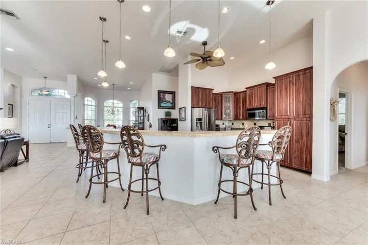 Kitchen with a breakfast bar, hanging light fixtures, ceiling fan, a large island, and stainless steel appliances