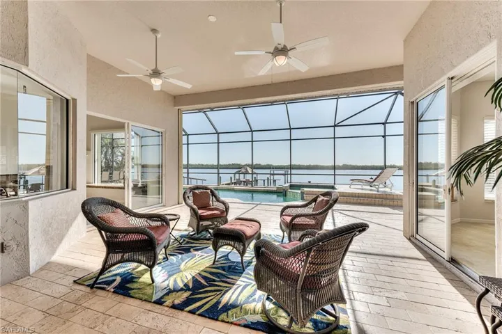 Sunroom featuring a water view, ceiling fan, and a swimming pool