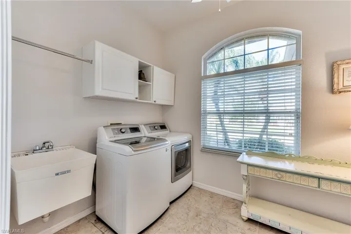 Laundry room with cabinets, washing machine and dryer, light tile patterned floors, and sink