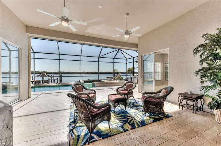 View of patio featuring a water view, glass enclosure, and ceiling fan