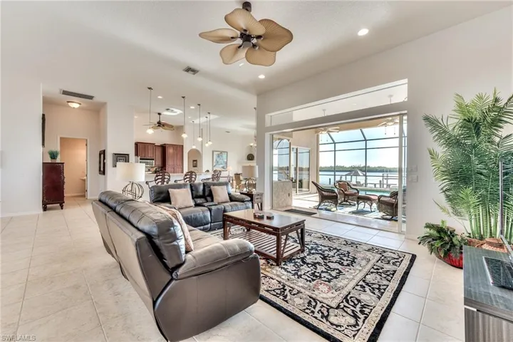 Tiled living room with ceiling fan and a water view