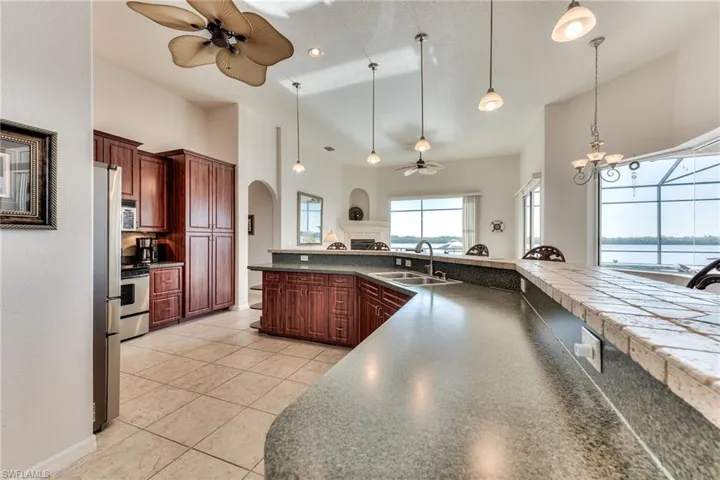 Kitchen featuring ceiling fan with notable chandelier, light tile patterned floors, sink, and hanging light fixtures