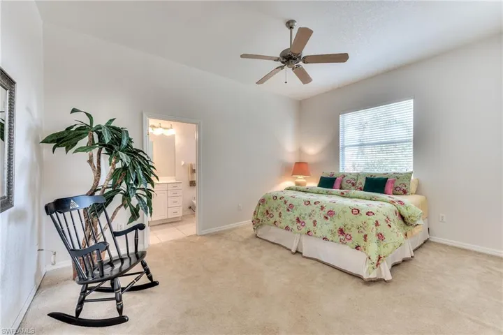 Carpeted bedroom with ensuite bathroom and ceiling fan