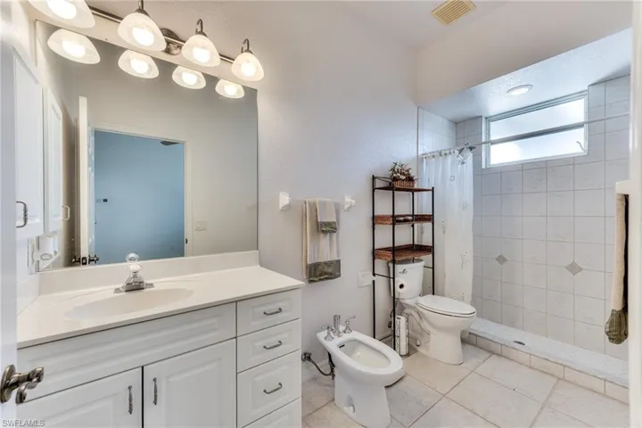 Bathroom featuring vanity, a bidet, a shower with shower curtain, tile patterned flooring, and toilet