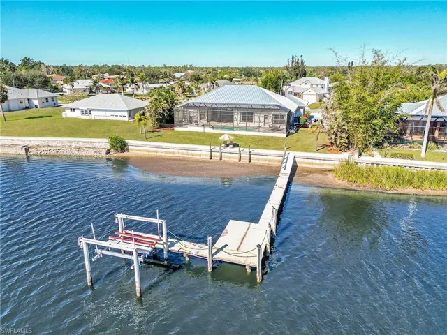 View of dock featuring a lanai, a yard, and a water view