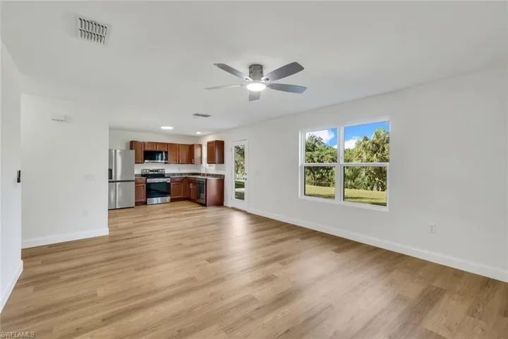 Unfurnished living room with ceiling fan, sink, and light hardwood / wood-style floors