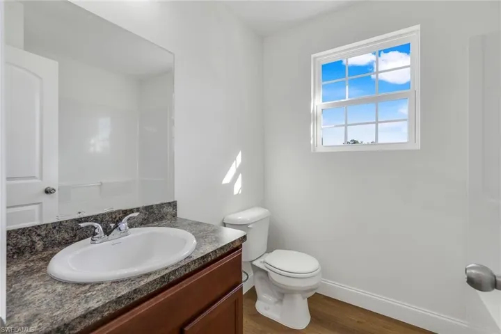 Bathroom with wood-type flooring, vanity, and toilet