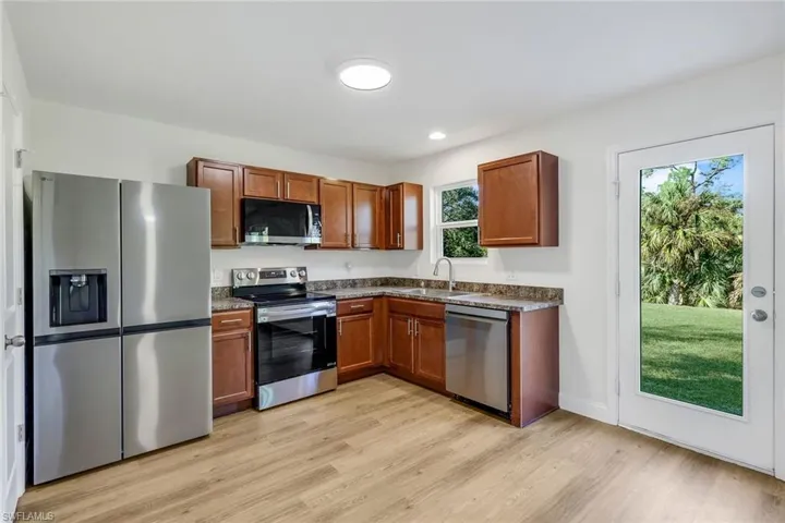 Kitchen featuring a healthy amount of sunlight, light wood-type flooring, sink, and appliances with stainless steel finishes