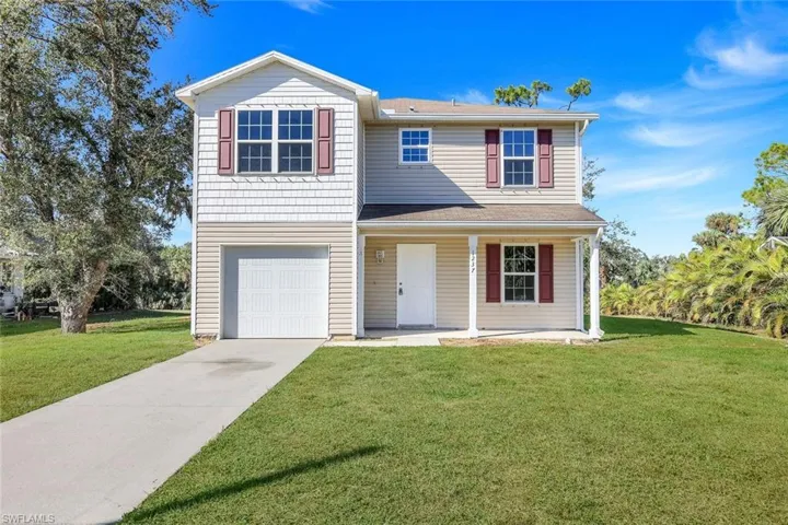 View of front of house featuring a front lawn, a porch, and a garage
