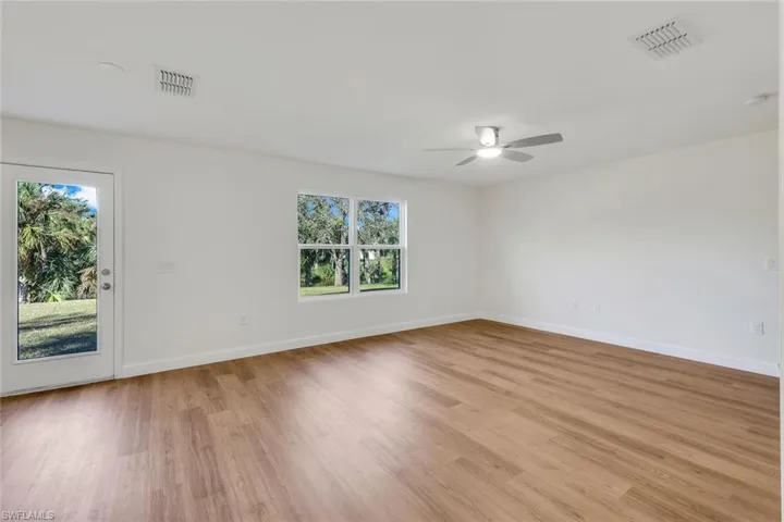 Unfurnished room with a wealth of natural light, ceiling fan, and light wood-type flooring
