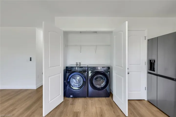 Washroom with washing machine and clothes dryer and light hardwood / wood-style flooring