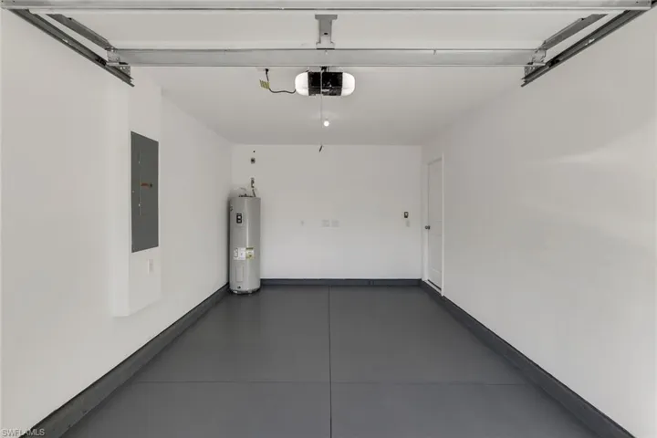 Garage featuring a garage door opener, electric water heater, and electric panel