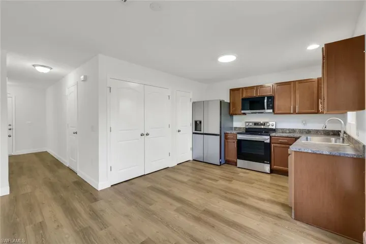 Kitchen with light hardwood / wood-style floors, sink, and stainless steel appliances