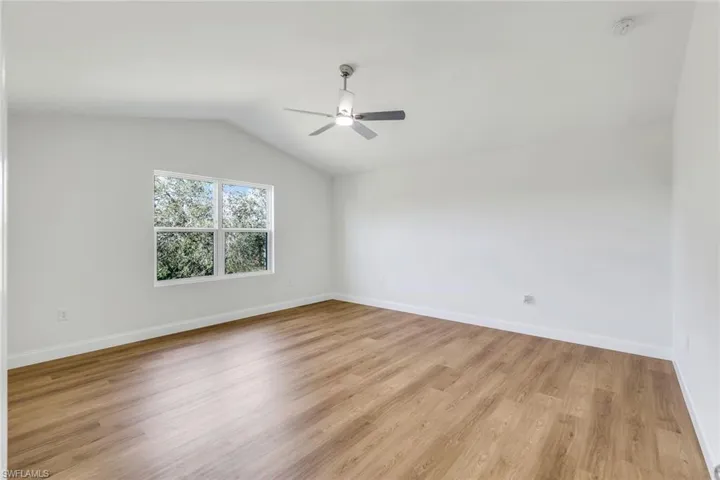 Unfurnished room featuring ceiling fan, light hardwood / wood-style floors, and vaulted ceiling