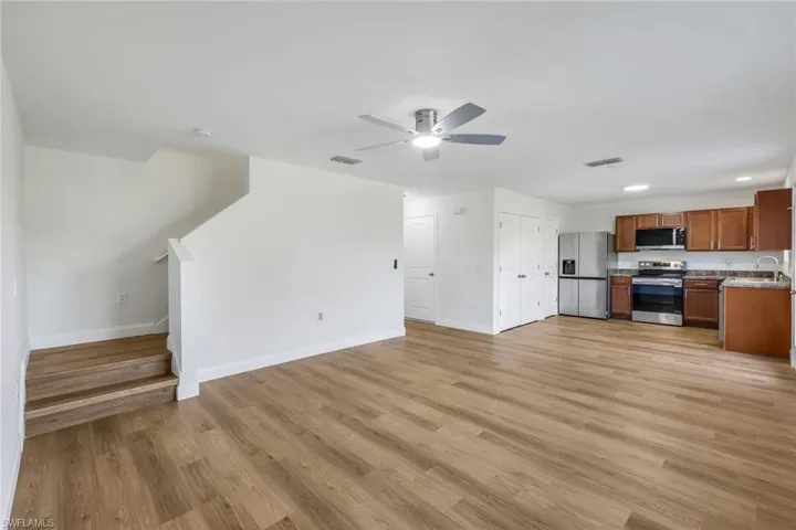 Unfurnished living room with ceiling fan, light wood-type flooring, and sink