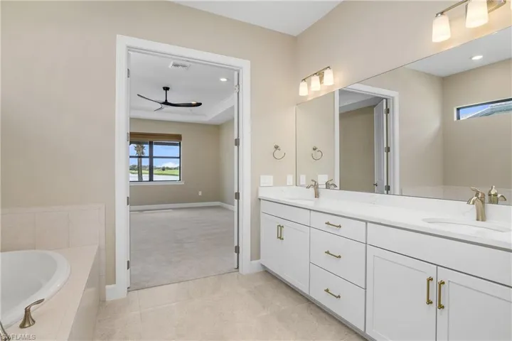 Bathroom with tile patterned flooring, tiled bath, and vanity