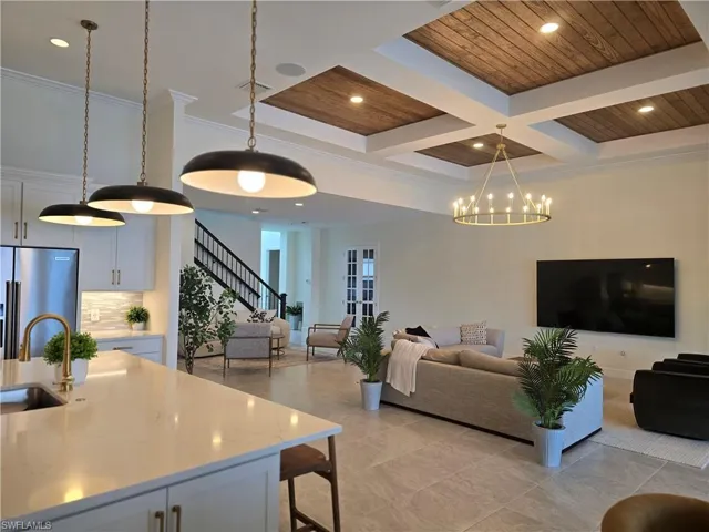 Kitchen featuring pendant lighting, backsplash, white cabinetry, coffered ceiling, and sink