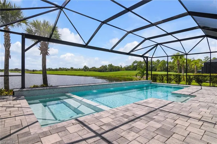View of swimming pool featuring  enclosure, a water view, and a patio