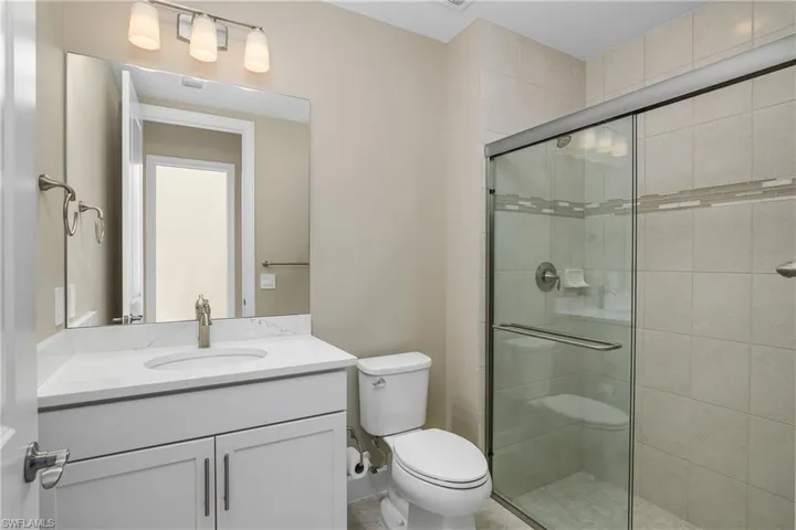 Bathroom featuring walk in shower with glass shower door next to bedroom 2