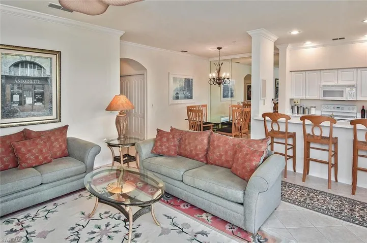 Living area featuring arched walkways, light tile patterned flooring, ornamental molding, a chandelier, and recessed lighting