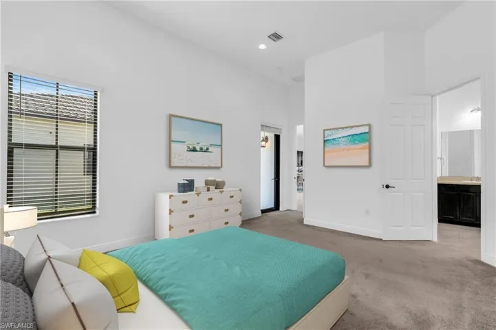 Carpeted bedroom featuring a high ceiling and connected bathroom