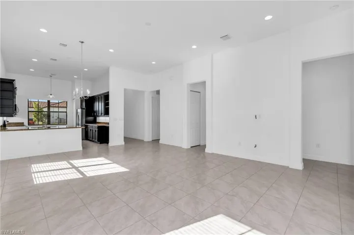 Unfurnished living room with light tile patterned floors and a notable chandelier