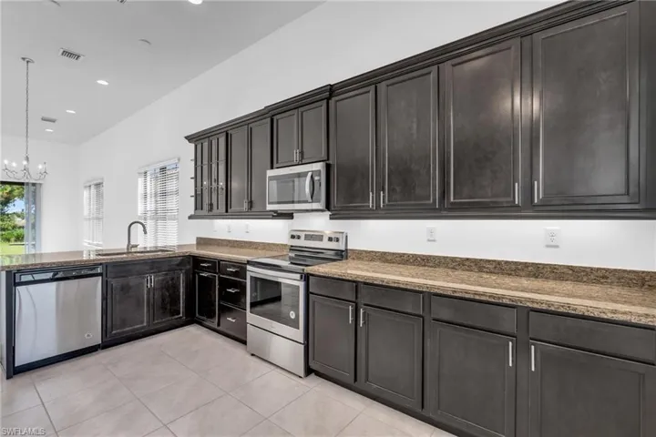 Kitchen with pendant lighting, a chandelier, light tile patterned floors, sink, and stainless steel appliances