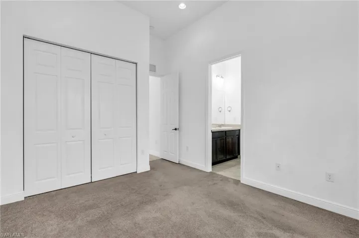 Unfurnished bedroom featuring a closet, sink, connected bathroom, and light colored carpet