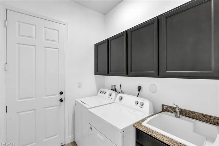 Clothes washing area featuring sink, independent washer and dryer, and cabinets