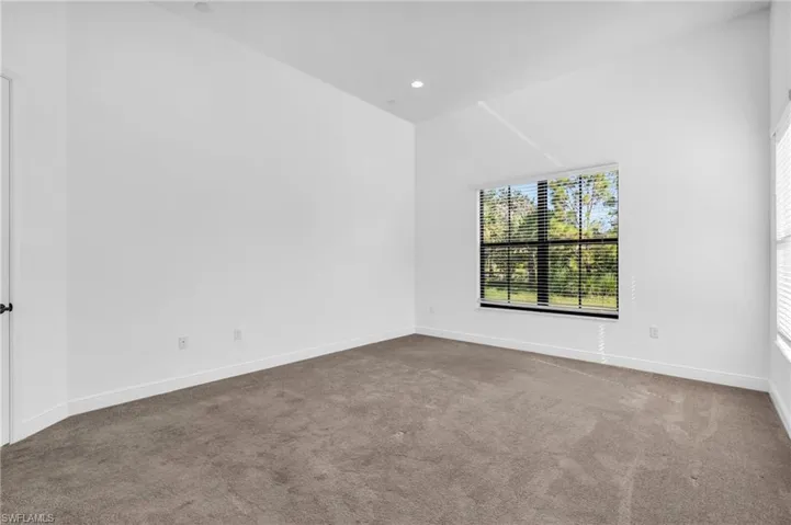Empty room with carpet flooring and vaulted ceiling