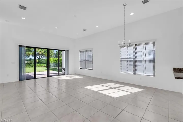 Empty room with light tile patterned floors and an inviting chandelier
