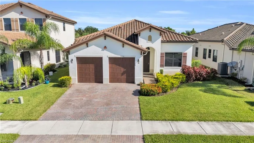 Mediterranean / spanish-style house with a front lawn, central AC unit, and a garage
