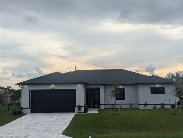 View of front facade featuring a garage and a lawn