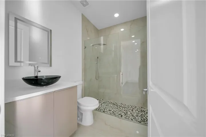 Bathroom with vanity, a marble finish shower, and recessed lighting