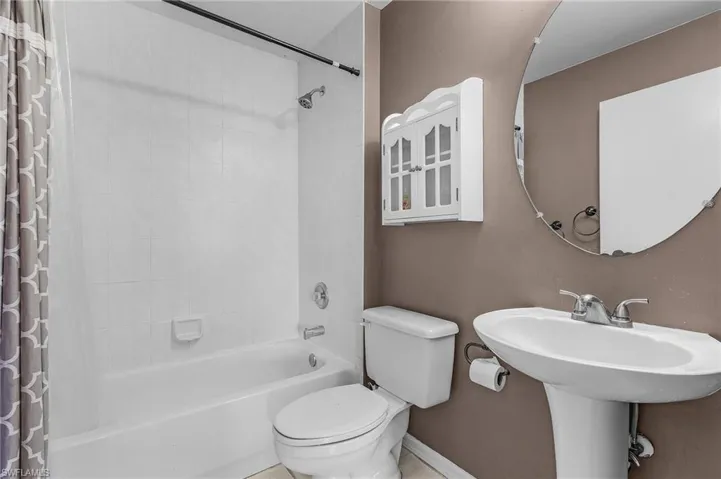 Bathroom featuring toilet, shower / bath combo, and tile patterned flooring