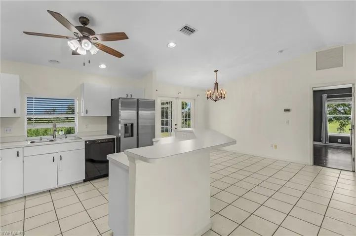 Kitchen with sink, dishwasher, stainless steel fridge, and white cabinetry