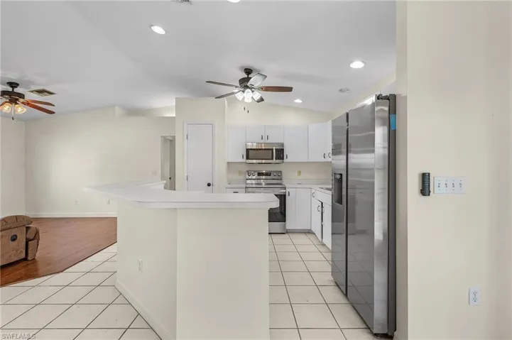 Kitchen featuring white cabinetry, ceiling fan, vaulted ceiling, appliances with stainless steel finishes, and light tile patterned floors