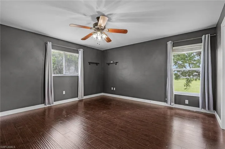 Empty room featuring ceiling fan, wood-type flooring, and plenty of natural light