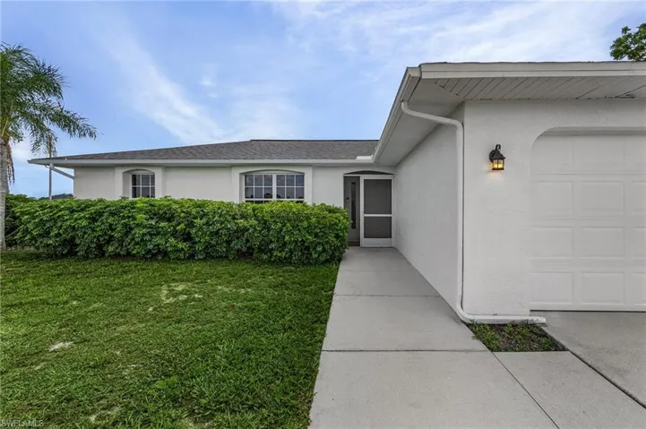 View of exterior entry featuring a garage and a yard