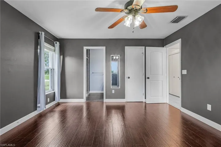 Unfurnished bedroom with ceiling fan, a walk in closet, and hardwood / wood-style flooring