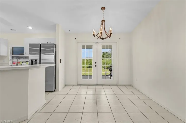 Kitchen with hanging light fixtures, white cabinets, light tile patterned floors, and french doors