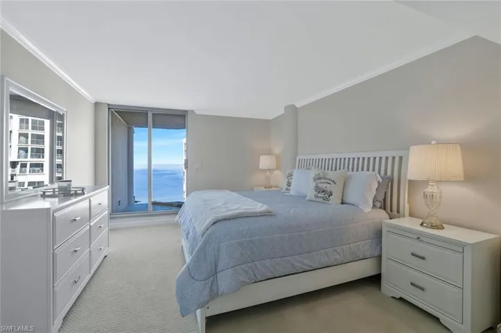 Carpeted bedroom featuring lanai, ornamental molding, and a fabulous water view.