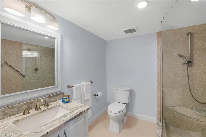 Primary Bathroom featuring large tiled shower, vanity, and toilet.